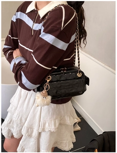 Detalle de bolso baguette de cuero acolchado negro con cadena dorada y colgante monstruo