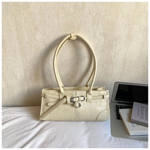 Detail view of cream rectangle handbag with decorative leather straps and metal buckles