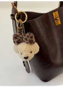 Detail of cute teddy plush bear charm with leopard bow on a leather bucket bag