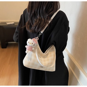 Détail du sac hobo à motif damier avec un charmant pendentif en peluche décoratif
