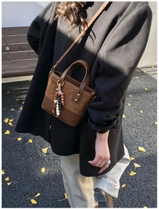 Close-up of brown suede crossbody bag with colorful bead tassels and logo detail
