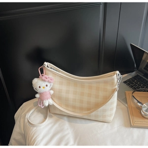 Détail du sac cabas à carreaux beige orné d'un joli pendentif en peluche sur le côté du sac