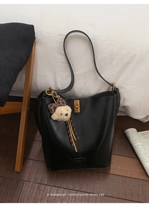 Close-up of black retro bucket bag featuring gold metal twist lock and cute bear charm
