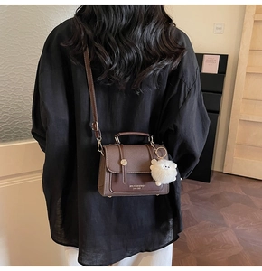 Brown vintage leather crossbody bag featuring a golden buckle and plush lamb charm