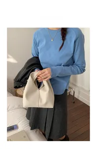 Détail du sac cabas en cuir grainé crème porté par un mannequin en tenue décontractée