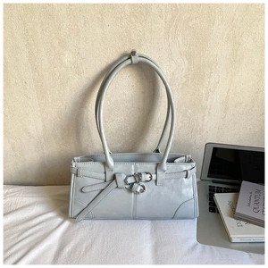 Detailed macro shot of light blue leather tote bag with decorative metal buckle and strap