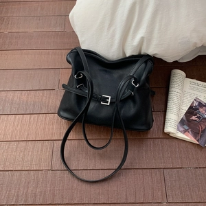 Détail de la boucle argentée et de la texture en cuir noir mat sur le sac à bandoulière souple