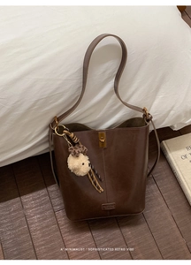 Detail of vintage brown leather bucket bag with gold clasp and plush puppy charm
