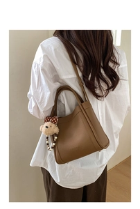 Detail of vintage brown leather bucket bag with teddy bear charm and adjustable strap