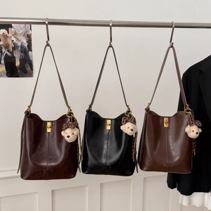 Three vintage leather tote bags in brown and black colors with bear keychain accessories