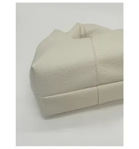Détail de la texture cuir grainé ivoire et coutures croisées durables sur le sac à main