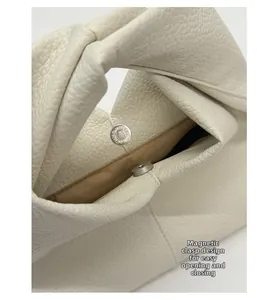 Détail d'un sac en cuir blanc à motif litchi avec un fermoir magnétique très pratique