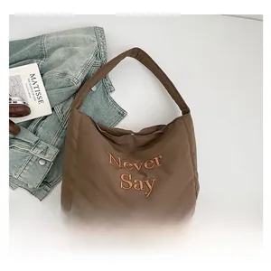 Flat lay of brown tote bag with Never Say Goodbye embroidery and stylish accessories