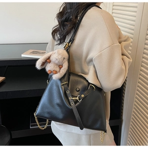Detailed side view of black matte leather tote bag with plush bunny charm and gold chain