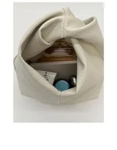 Vue détaillée du grand sac cabas en cuir beige avec tablette et cosmétiques à l'intérieur
