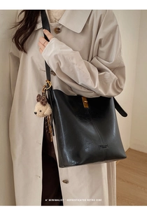 Close-up of black retro bucket bag with gold metal clasp and plush bear charm detail