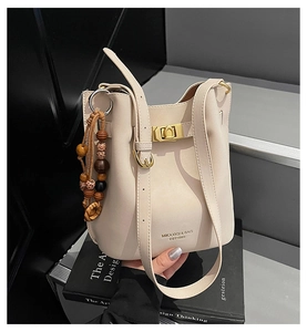 Détail du sac seau blanc crème avec fermoir doré et pendentif à pompon léopard en perles