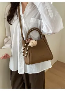 Brown lychee texture bucket bag shown on shoulder with bear charm and colorful beads