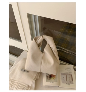 Détail du sac à main blanc crème avec texture grainée et poignée nouée minimaliste