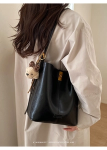 Detail of black leather tote bag with gold twist lock and cute plush bear charm