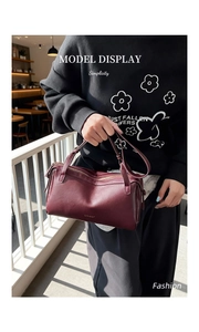 Close-up of a burgundy leather baguette bag with metal zipper and adjustable strap