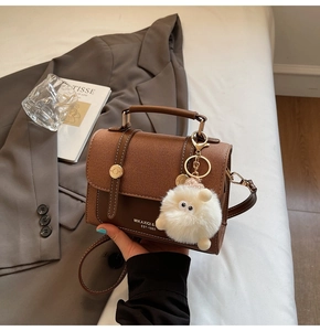 Detail of vintage brown square bag with golden buckle and cute white plush sheep charm