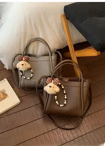 Close-up of pebble leather bucket bags with pearl charms and cute puppy keychains