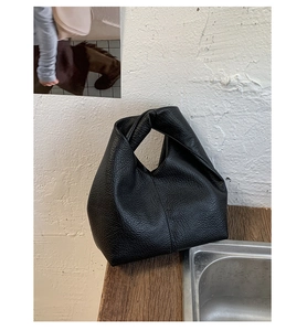 Détail d'un sac cabas noir en cuir avec poignée nouée unique et texture en cuir grainé