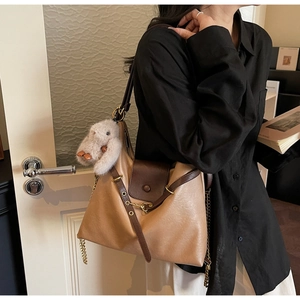 Detail of vintage tote bag with contrast leather, gold chain strap, and plush rabbit charm