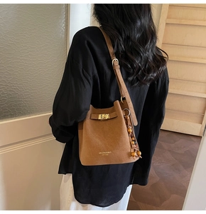 Détail du sac seau en daim marron avec fermoir doré et pampille en perles de bois