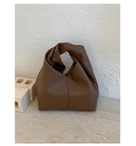 Détail du sac en cuir marron foncé montrant la texture grainée et la poignée nouée