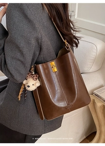 Brown retro leather bucket bag detail with gold clasp and leopard bow plush bear charm