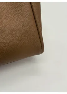 Close-up of premium brown litchi grain leather texture and high-quality rolled edge seams