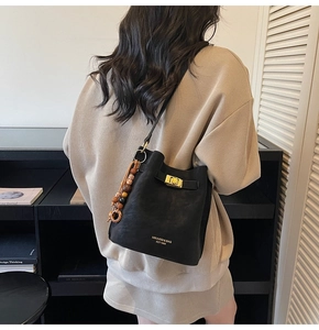 Détail d'un sac seau en cuir noir avec fermoir doré et pendentif en perles ethniques