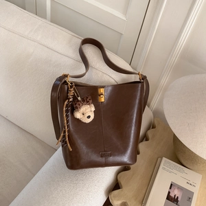 Close-up of vintage brown leather bucket bag with gold clasp and cute bear charm accessory