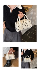 Detail of white polka dot handbag showing detachable strap and polished metal logo plate
