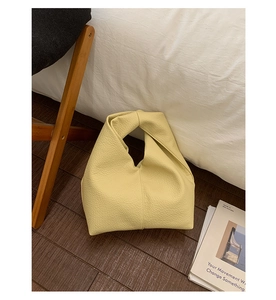Détail du sac à main en cuir grainé jaune clair avec une poignée nouée unique