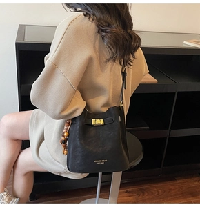 Détail du sac seau en cuir noir avec boucle en métal et perles en bois décoratives