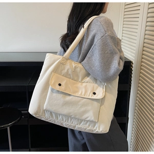 Detail of a large cream tote bag with a double button front pocket on a female model