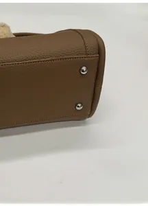 Detailed close-up of wide bag base with silver studs and lychee pattern leather