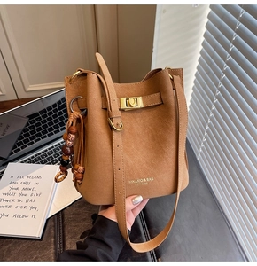 Détail du sac seau marron chaud avec texture cuir rétro et breloque à pampilles perlées