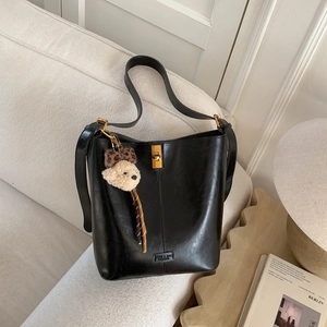 Detail of black oil-wax leather bucket bag with gold buckle and leopard bear charm