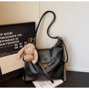 Detail of black PU leather tote bag with gold chain and plush rabbit charm accessory