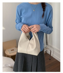 Détail du sac à main minimaliste en cuir crème avec une texture grainée délicate