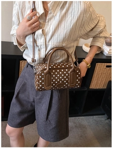 Detailed macro view of the glossy brown polka dot Boston bag and polished PU leather texture
