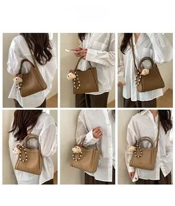 Close-up of brown litchi pattern PU leather bucket bag with polka dot bow bear charm