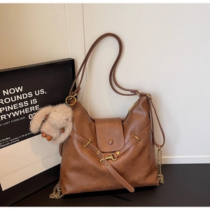 Detail of brown hobo tote bag featuring dual straps, chain decor and plush bunny charm