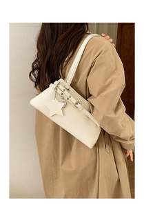 Détail du sac Boston crème avec breloque étoile et sangles réglables sur le modèle