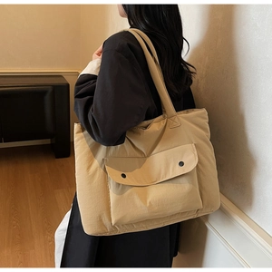 Detail of khaki nylon tote bag with functional double-button outer pocket and shoulder strap