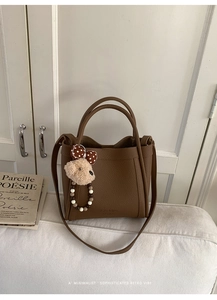 Detail of dark brown lychee leather bucket bag with teddy charm and beaded handle